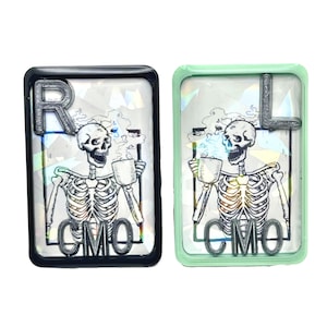 May include: Two black and green resin framed images of a skeleton drinking coffee with the letters "R" and "L" and the text "CMO" on each image.