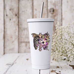 May include: White stainless steel tumbler with a floral design featuring a ribcage and flowers in shades of pink, yellow, and purple.