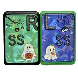 May include: Two Halloween-themed keychains. One is green with a ghost holding a jack-o'-lantern, the letter "R", and the letters "SS". The other is blue with a spider, a ghost with a pumpkin, the letter "L", and the letters "SS".