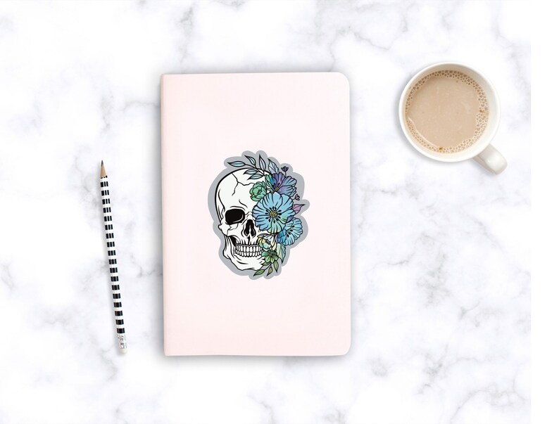 May include: A white skull with blue and green flowers covering one eye. The skull is outlined in black and the flowers are detailed with shading.