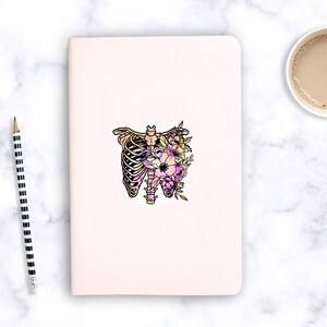 May include: A sticker featuring a colourful illustration of a ribcage with flowers growing inside. The ribcage is outlined in black and filled with a gradient of pink, yellow, and orange. The flowers are pink, purple, and white.
