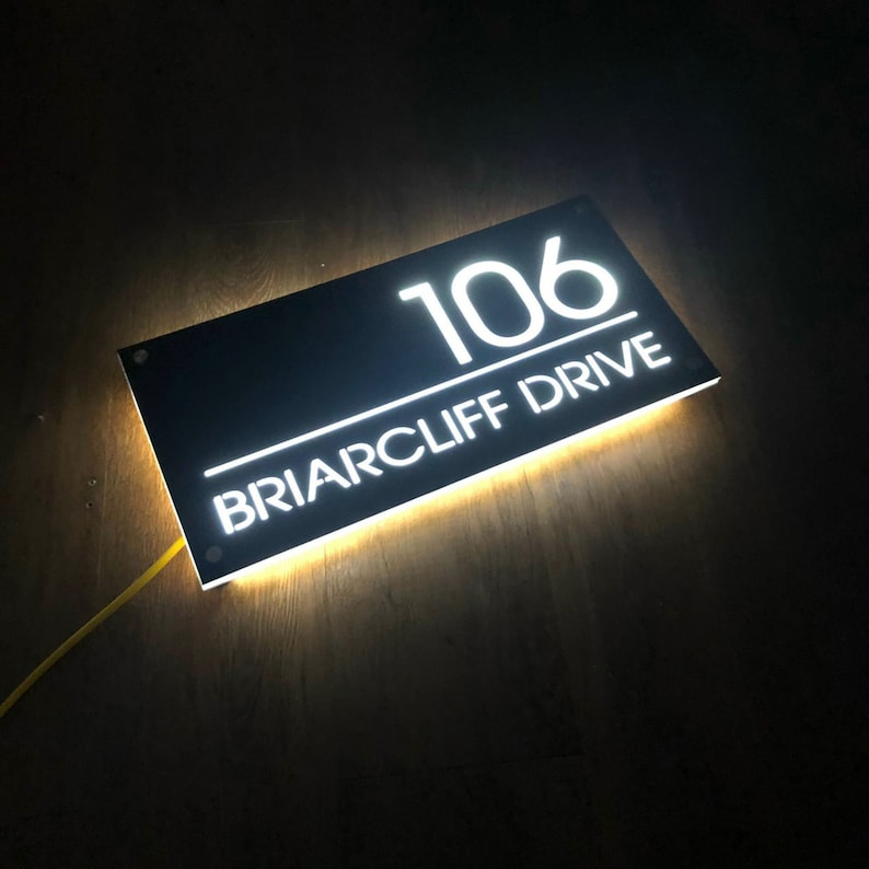 Pu&ograve; includere: Un cartello di numero civico nero illuminato con lettere bianche. Il cartello recita "106 Briarcliff Drive".