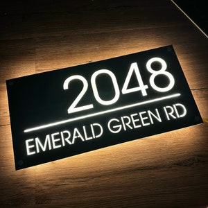 May include: Black house number sign with white illuminated lettering. The number 2048 and the street name "EMERALD GREEN RD" are displayed.