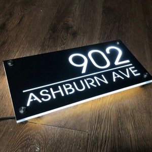 Pu&ograve; includere: Cartello per numeri civici in acrilico nero con lettere bianche illuminate. Il cartello recita "902 ASHBURN AVE".