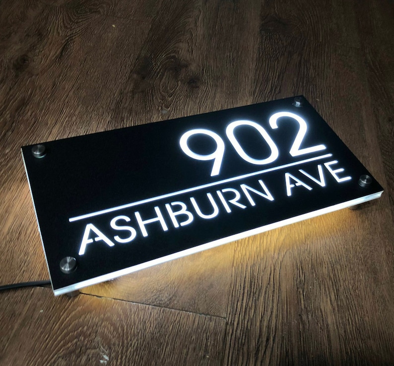 Pu&ograve; includere: Cartello per numeri civici in acrilico nero con lettere bianche illuminate. Il cartello recita "902 ASHBURN AVE".