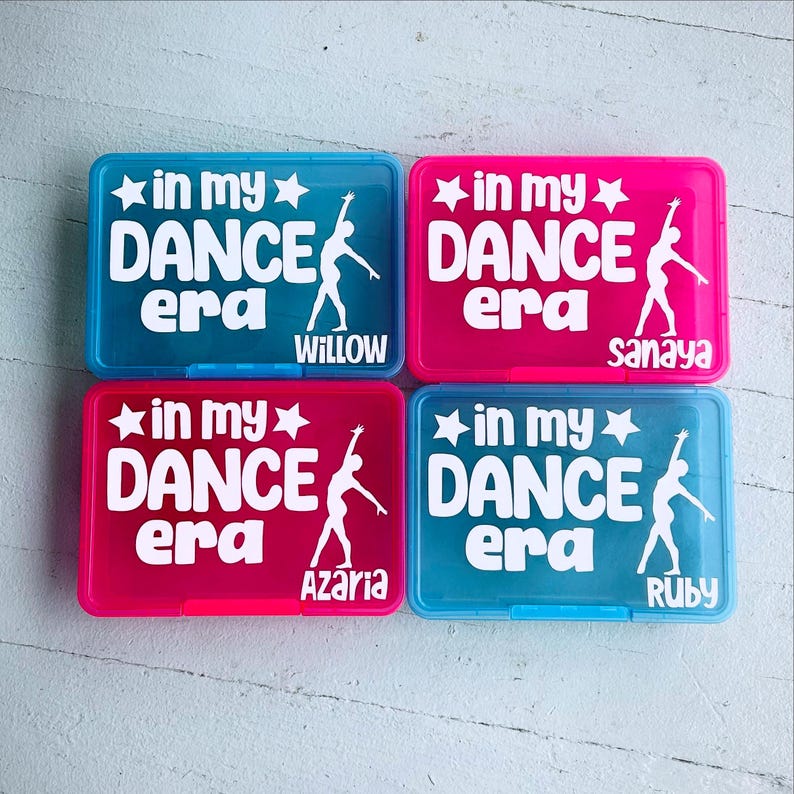 May include: Four rectangular plastic boxes in blue and pink. Each box has the text "in my DANCE era" with a star and a dancer silhouette in white. Names Willow, Sanaya, Azaria, and Ruby are printed below.