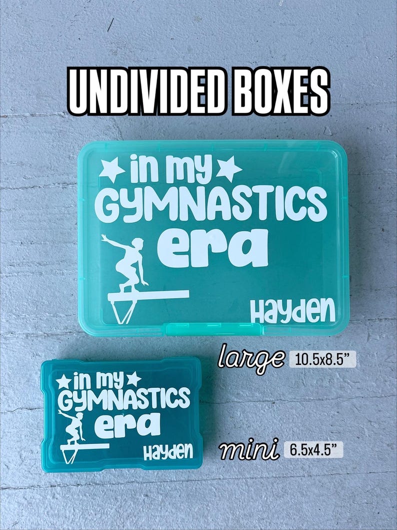May include: Two teal plastic storage boxes, one large and one mini, with white text that reads "UNDIVIDED BOXES" and "in my GYMNASTICS era." The large box measures 26.7x21.6 cm, and the mini box measures 16.5x11.4 cm. Both boxes have the name "Hayden" on them.