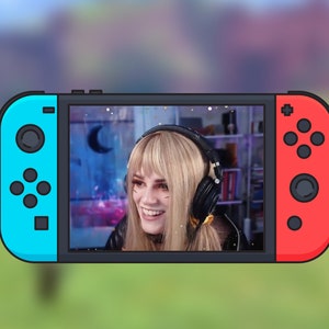 Op de afbeelding: Een vrouw met blond haar en een zwart leren jack lacht terwijl ze een koptelefoon draagt. Ze is in een videogesprek op een blauwe en rode Nintendo Switch.