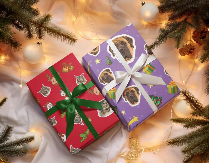 May include: Two wrapped gifts with festive patterns and ribbons. One is red with cat and holiday graphics, tied with a green ribbon. The other is purple with dog faces, tied with a white ribbon. Christmas tree branches and ornaments surround the gifts.