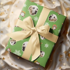 May include: A wrapped gift with green wrapping paper featuring dog faces, snowflakes, and gnome illustrations. The gift is tied with a cream-colored ribbon and bow. The background is a cream-colored fabric with gold star accents.