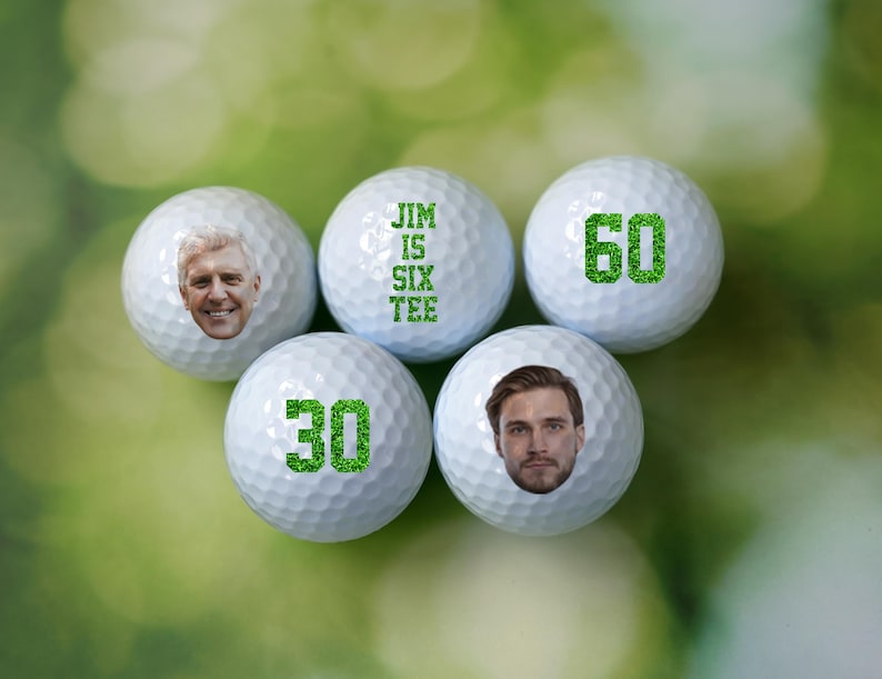 May include: Six white golf balls with green text and images. One ball says "Jim is Six Tee", another says "60", another says "30", and two have a person's face on them.