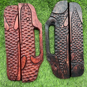 May include: Two wooden wall hangings with a carved fish design. One is dark brown and the other is a reddish brown.
