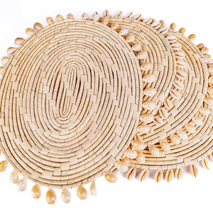 May include: Three round woven placemats with a natural beige color and a decorative border of small white seashells.