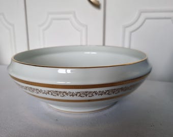 May include: A white porcelain bowl with a gold rim and a decorative gold band around the middle. The bowl has a wide, shallow shape and a slightly flared rim. The gold band features an ornate, repeating pattern.