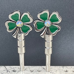 May include: Two silver keychains with green four-leaf clover charms and clear rhinestone accents.