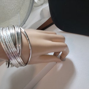 May include: A silver bracelet with multiple bands, some with a textured finish.