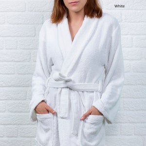 May include: White bathrobe with a shawl collar, long sleeves, and two pockets. The robe is tied at the waist with a sash.