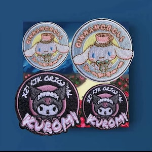 Puede incluir: Cuatro parches bordados con personajes de dibujos animados. Dos parches circulares muestran un personaje azul claro con el texto "CINNAMOROLL". Los otros dos parches muestran un personaje negro con el texto "KUROMI".