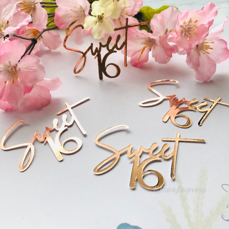 Puede incluir: Confetti de purpurina dorado rosa con las palabras "Sweet 16" en una fuente de escritura.