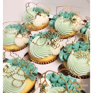May include: A close-up of cupcakes decorated with green and white frosting and gold animal toppers. The cupcakes are arranged in a white cupcake holder. The text "Cupcakes by Wynnte @sugar_pushka" is visible in the bottom right corner of the image.