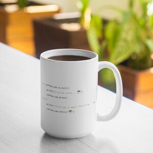 Op de afbeelding: Een witte keramische mok met zwarte en gekleurde programmeercode-tekst: if coffee_cup.is_full(): print("Drinking coffee...") coffee_cup.drink() else: print("Coffee cup is empty. Refilling...") coffee_cup.refill() met kleine koffiekop-pictogrammen.