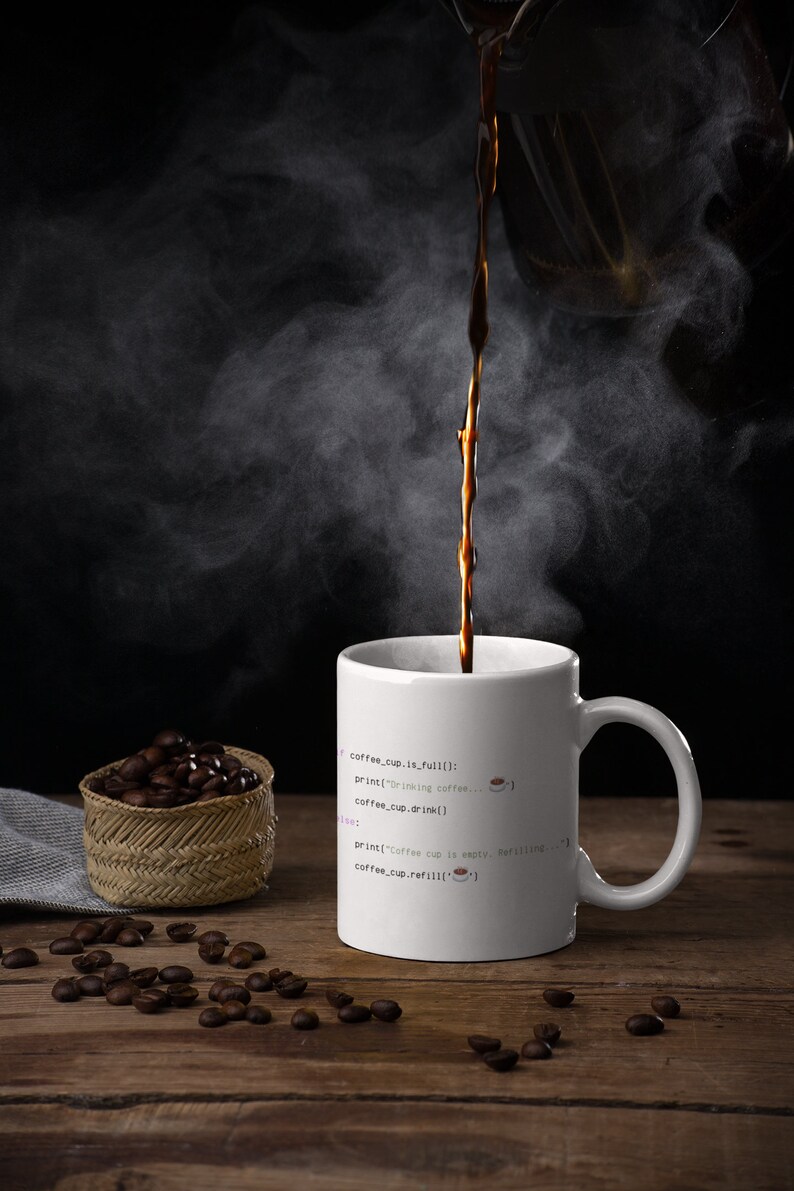 Op de afbeelding: Een witte keramische mok met geprinte programmeercode: if coffee_cup.is_full(): print("Drinking coffee...") coffee_cup.drink() else: print("Coffee cup is empty. Refilling...") coffee_cup.refill(). Donkere koffie wordt in de mok geschonken.