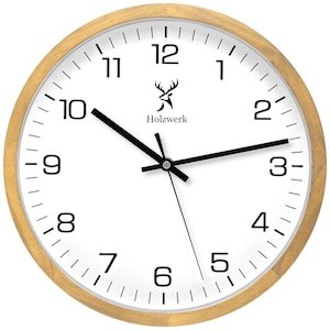 Op de afbeelding: Een witte analoge klok met zwarte wijzers en zwarte Romeinse cijfers. De klok heeft een houten frame en een hertenlogo met de tekst "Holzwerk" bovenaan.