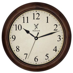 Puede incluir: Un reloj de pared redondo con un marco de madera marrón oscuro. La esfera del reloj es blanquecina con números y manecillas negras. El reloj marca las 10:10. La marca "Holzwerk" está impresa en la esfera.