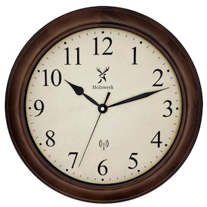 Könnte beinhalten: Eine runde Wanduhr mit einem dunkelbraunen Holzrahmen. Das Zifferblatt ist cremefarben mit schwarzen Ziffern und Zeigern. Die Uhr zeigt 10:10 Uhr an. Der Markenname "Holzwerk" ist auf dem Zifferblatt aufgedruckt.