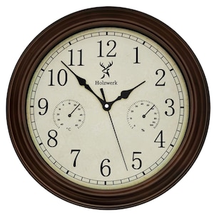 May include: A round brown wall clock with a cream-coloured face. The clock features black numerals, black hands, and two smaller dials for temperature and humidity. The brand name "Holzwerk" is printed on the face.