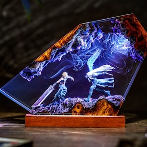 Peut inclure: Une sculpture en résine représentant une scène de bataille avec deux personnages à l'intérieur d'un bloc clair et angulaire. Les personnages sont bleus et blancs, avec une grande épée. La base est un bloc de bois rectangulaire, et le fond est un mélange de bleu et de marron.