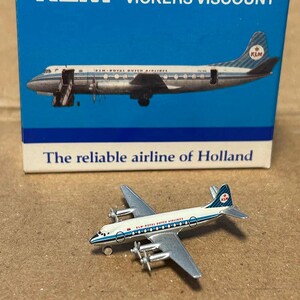 Könnte beinhalten: Ein Miniatur-Metallmodell eines KLM Vickers Viscount Flugzeugs mit weiß-blauer Lackierung, vier Propellern und dem KLM-Logo auf dem Leitwerk. Es wird vor seiner originalen blau-weißen Kartonverpackung präsentiert.