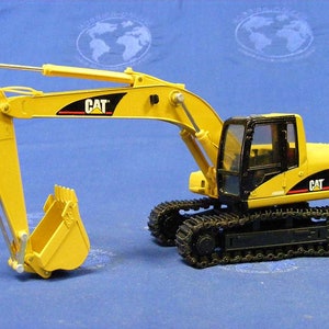 Pode incluir: Um brinquedo escavador Caterpillar 320C amarelo e preto com uma cabine preta e uma ca&ccedil;amba amarela. O escavador est&aacute; em uma esteira preta.