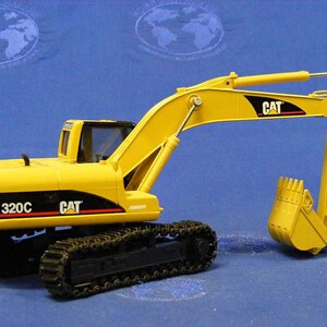 Pode incluir: Modelo de brinquedo de escavadora Caterpillar 320C amarela com esteiras pretas e uma ca&ccedil;amba amarela. O modelo tem o logotipo CAT no lado e o n&uacute;mero do modelo 320C na frente.