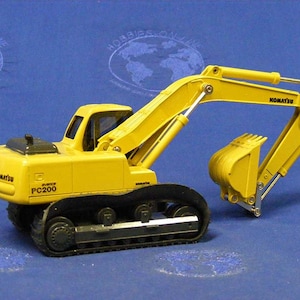 May include: Yellow toy excavator with black tracks and a black Komatsu logo. The excavator has a black and silver arm with a yellow bucket. The excavator is labeled "PC200".