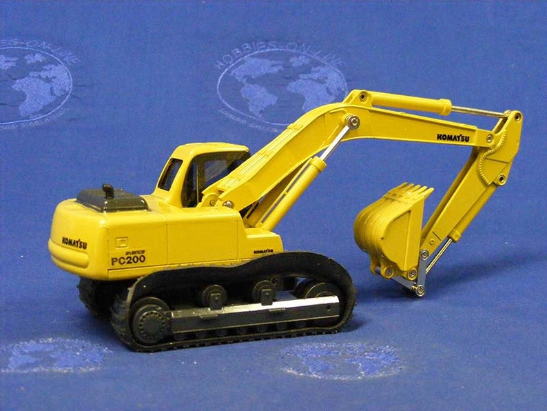 May include: Yellow toy excavator with black tracks and a black Komatsu logo. The excavator has a black and silver arm with a yellow bucket. The excavator is labeled "PC200".