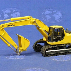May include: Yellow toy excavator with black tracks and a black cab. The excavator has the word "KOMATSU" on the arm and "PC200" on the side.