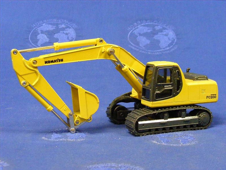 May include: Yellow toy excavator with black tracks and a black cab. The excavator has the word "KOMATSU" on the arm and "PC200" on the side.