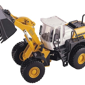 Op de afbeelding: Geel en zwart speelgoed bouwvoertuig met een witte cabine en het woord "LIEBHERR" aan de zijkant. Het voertuig heeft een grote zwarte schep en het nummer "564" staat op de arm gedrukt.