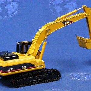 Puede incluir: Modelo de juguete de excavadora Caterpillar 325D amarilla con orugas negras y un brazo levantado. El modelo tiene una cabina negra y una cuchara amarilla.