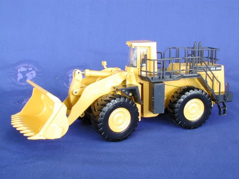 May include: A yellow and black toy model of a large front-end loader with a black safety cage and the text "WA 500" on the side.