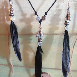 Elaborado conjunto de pendientes y collar en imitación plumas de cuervo, cuentas en metal plateado y colgantes pequeños.