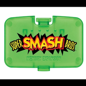 May include: A translucent lime green rectangular memory expansion pack for a video game console. The front features the text Super Smash Bros. in yellow and red letters with a black jagged outline, and the words Memory Expansion below it.