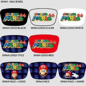 Op de afbeelding: Een verzameling Super Mario 64-accessoires. De ontwerpen omvatten het Super Mario 64-logo in verschillende kleuren, en sommige tonen Mario's gezicht. De tekst "SM64" en "Super Mario 64" zijn zichtbaar.