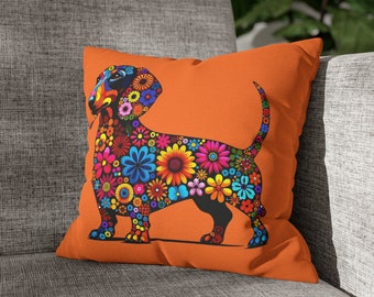 May include: Square orange cushion with a dachshund design made of colourful flowers. The dog's outline is filled with blue, yellow, pink, and orange blooms. The cushion is on a grey sofa.
