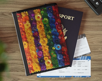 May include: A black passport holder with a colourful floral design. The design features a rainbow of flowers, including red, orange, yellow, green, blue, indigo, and violet. The holder is lying on top of a passport and a boarding pass.