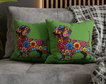 May include: Two green cushion covers featuring a floral dachshund design. The dachshund is black with colourful flowers covering its body.