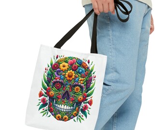 May include: A white tote bag with black handles features a colourful skull design made of flowers. The skull is surrounded by green leaves and colourful flowers.