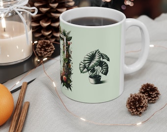 May include: White ceramic mug with a green background and a floral design. The mug features a black and white illustration of a plant in a pot. The text "It's the little things" is visible on the mug.
