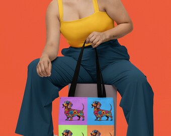 May include: A woman wearing a yellow tank top and blue trousers is sitting on a box holding a tote bag with a colourful floral dachshund design. The bag has four panels with a different dachshund on each panel.
